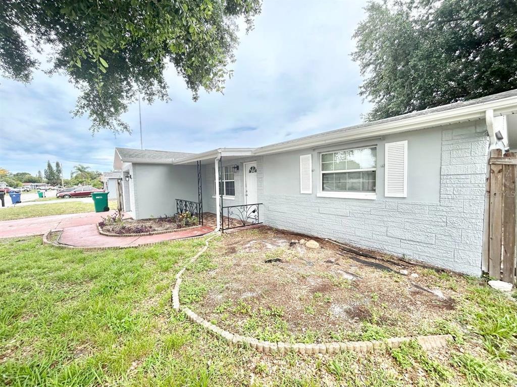 A light gray single-story house features a front porch, stone-textured siding, and a dirt yard — 3323 FAIRMOUNT DRIVE, HOLIDAY, FL