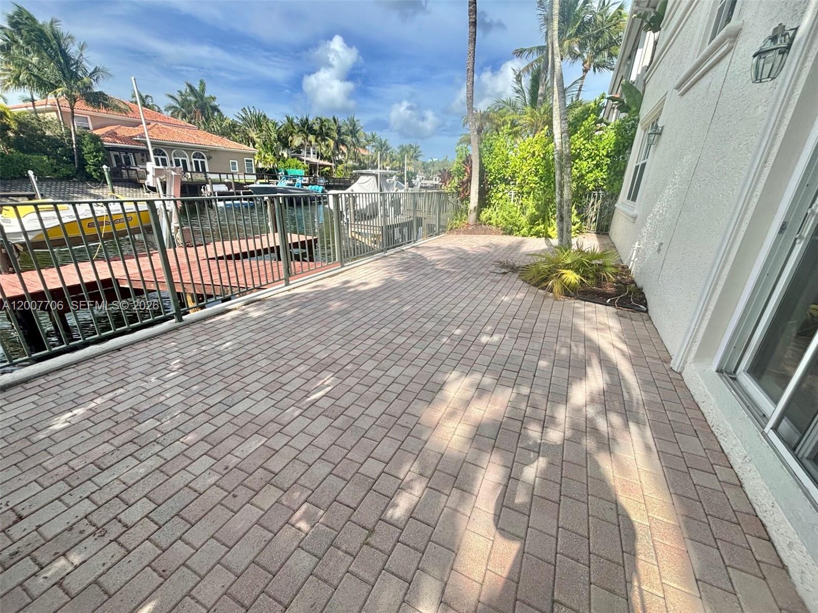 A paved patio overlooks a canal with a boat dock and metal railing — 1141 Waterside Ln, Hollywood FL 33019, HOLLYWOOD, FL