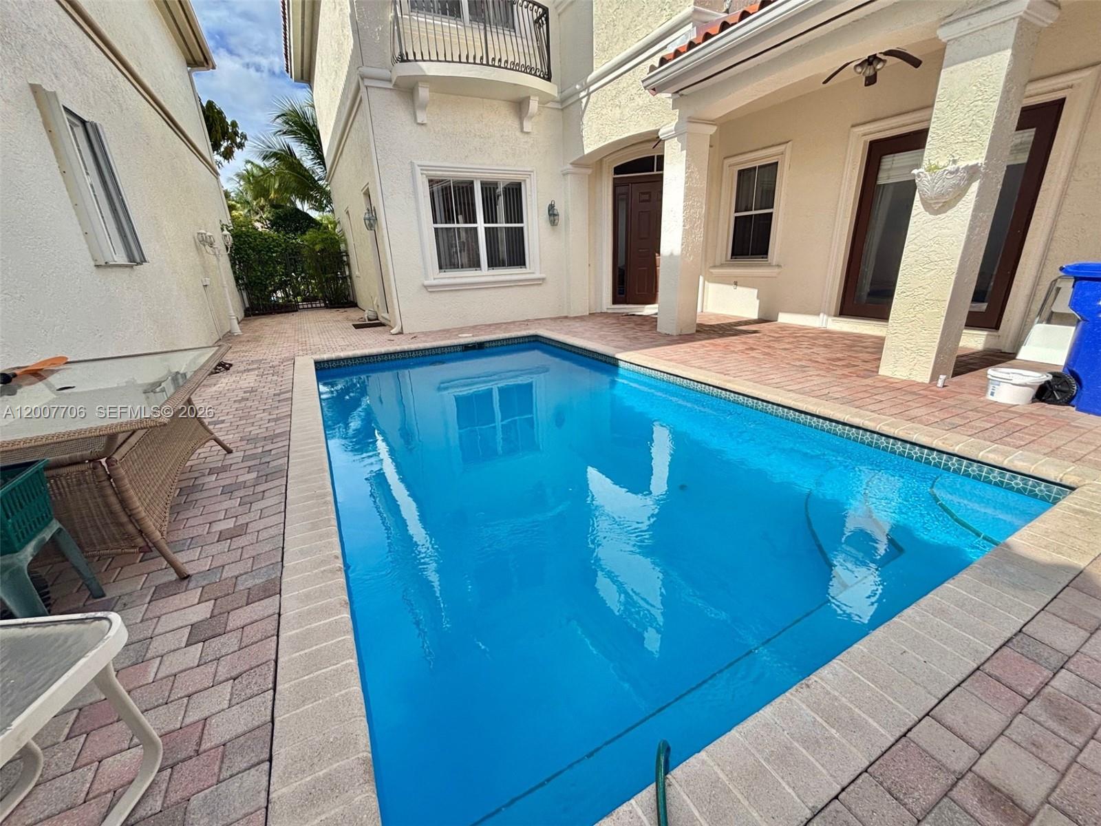 A rectangular swimming pool sits on a brick patio beside a two-story stucco house — 1141 Waterside Ln, Hollywood FL 33019, HOLLYWOOD, FL