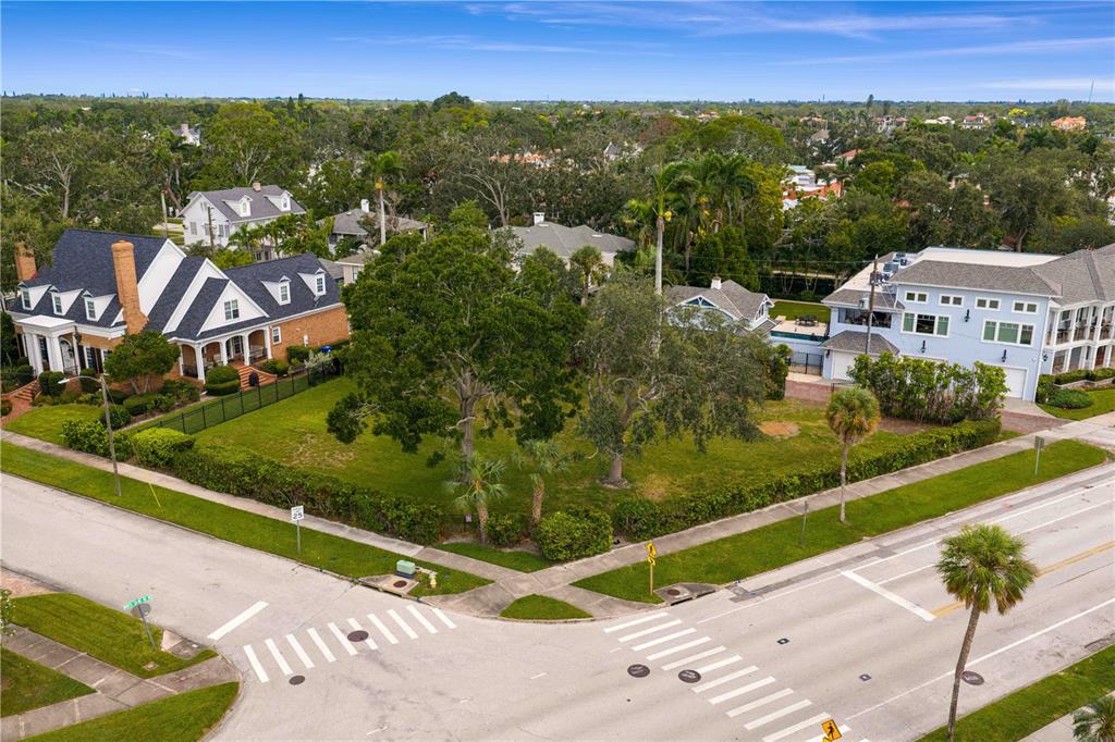 An aerial view shows a vacant grassy corner lot situated between two large residential homes — 1500 N SHORE DRIVE NE, ST PETERSBURG, FL