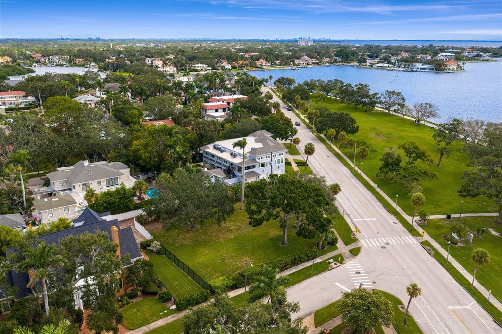 An aerial view shows a multi-story house near a road, green lawns, and a bay — 1500 N SHORE DRIVE NE, ST PETERSBURG, FL