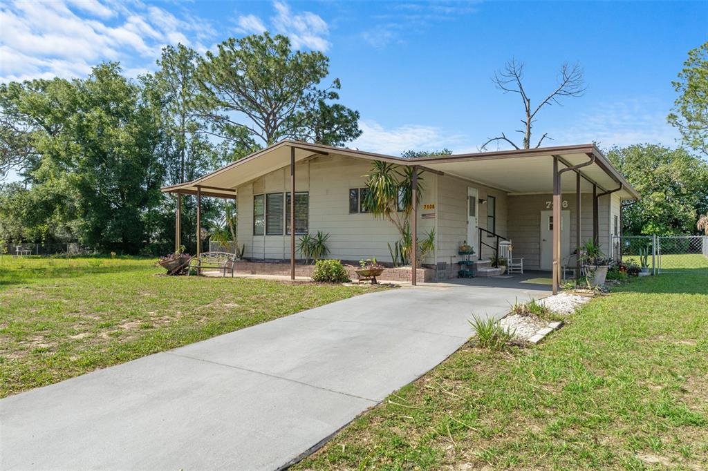 A single-story house with tan siding, a concrete driveway, and an attached carport — 7106 FITZPATRICK AVENUE, BROOKSVILLE, FL