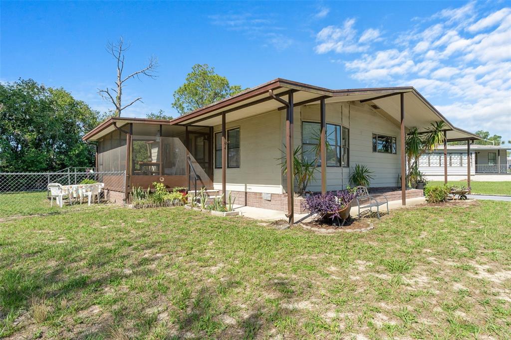A single-story mobile home features a screened-in porch, a metal roof, and a grassy yard — 7106 FITZPATRICK AVENUE, BROOKSVILLE, FL