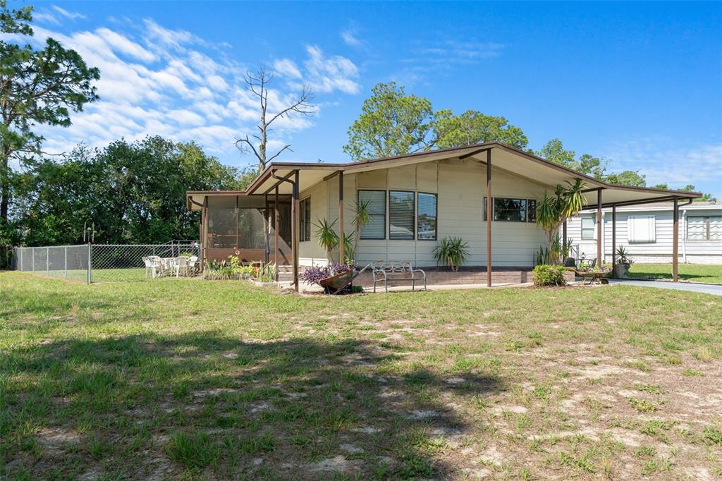 A single-story house with a screened porch, metal carport, and a chain-link fenced yard — 7106 FITZPATRICK AVENUE, BROOKSVILLE, FL