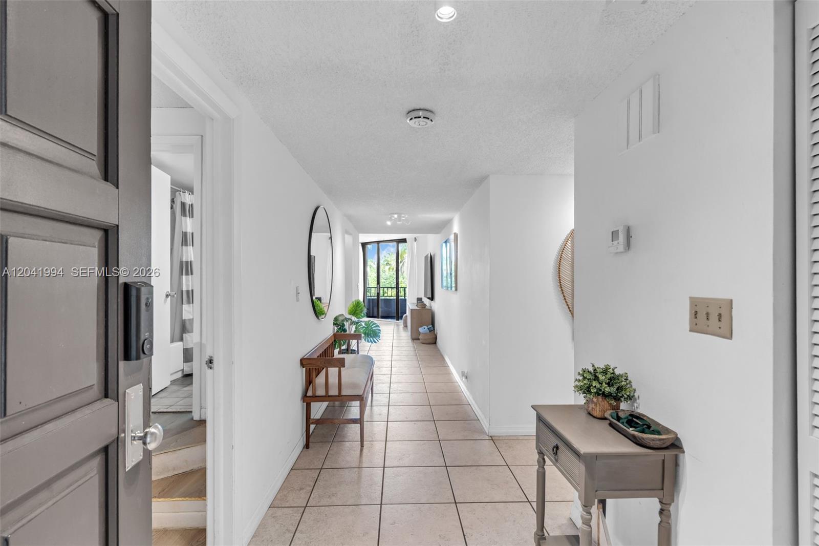 A tiled hallway leads from an entryway toward a balcony with a view of trees — 101 Crandon Blvd # 269, Key Biscayne FL 33149, KEY BISCAYNE, FL