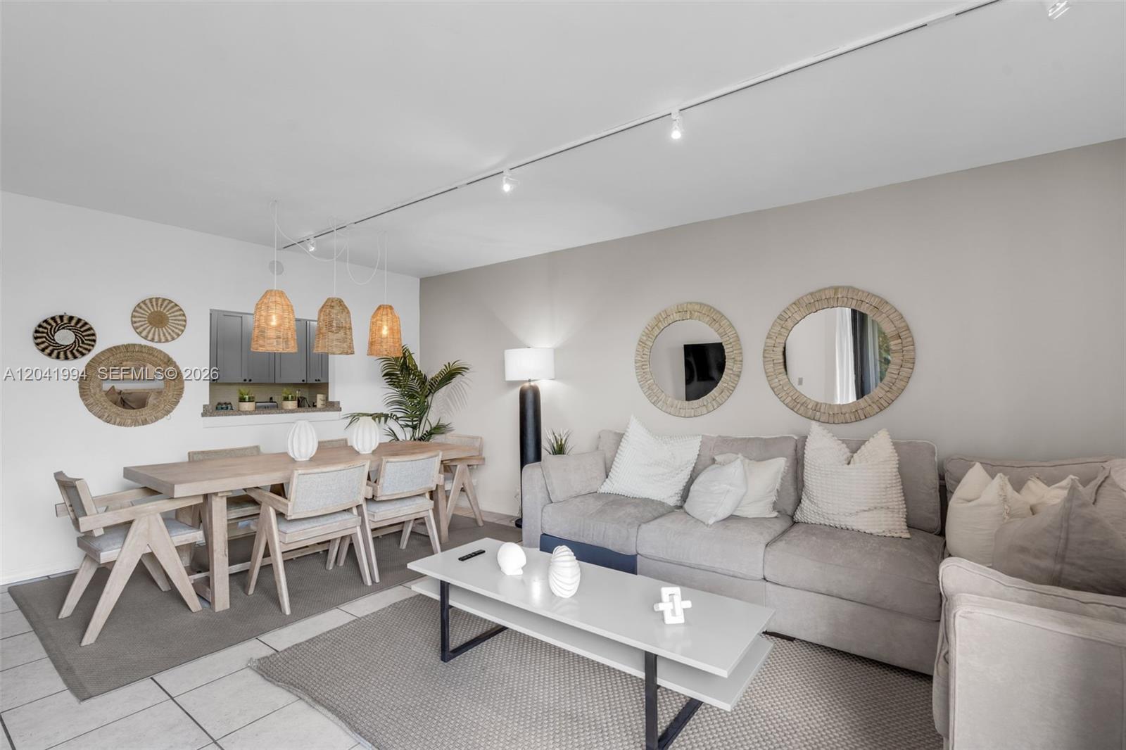 A living and dining room features a gray sofa, wooden table, and circular wall mirrors — 101 Crandon Blvd # 269, Key Biscayne FL 33149, KEY BISCAYNE, FL