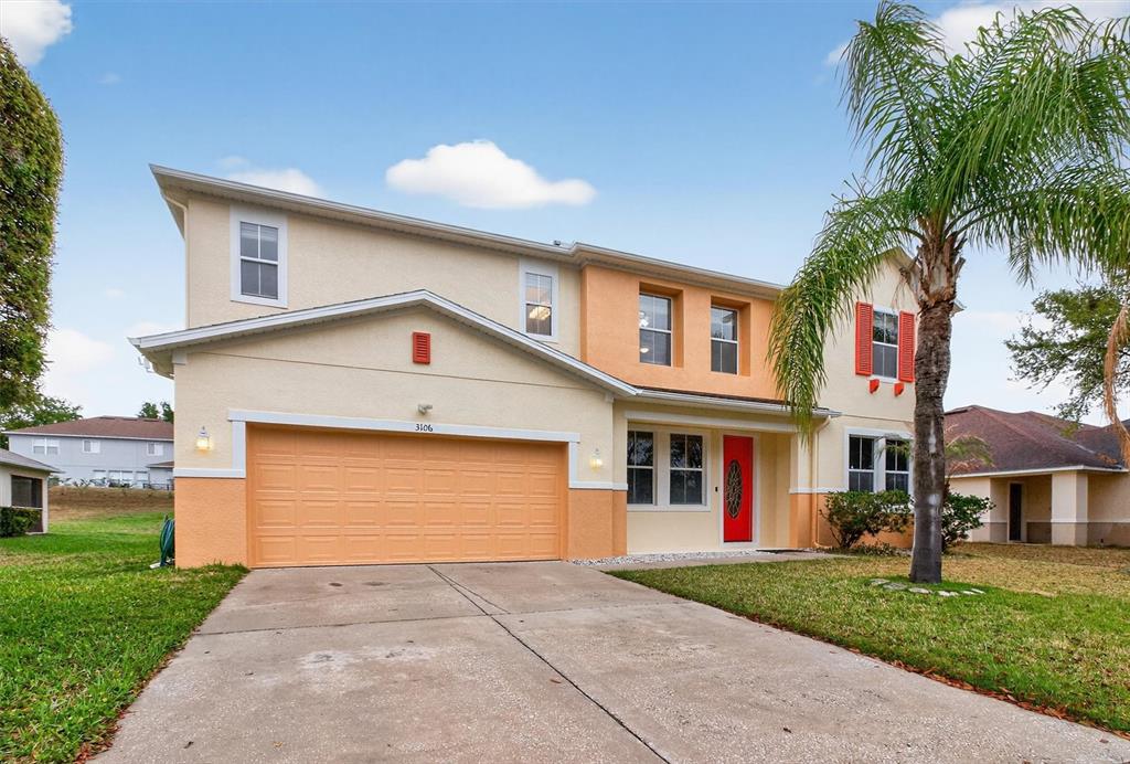 A two-story house with a two-car garage, stucco exterior, and a red front door — 3106 ANQUILLA AVENUE, CLERMONT, FL