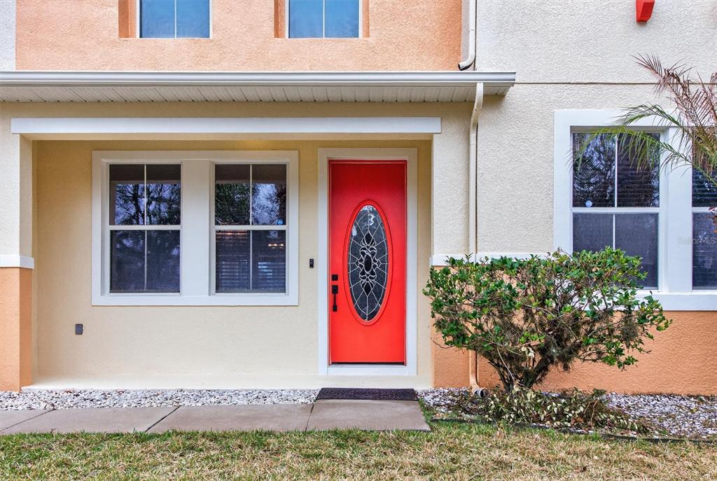 The exterior of a house features a bright red front door and a small bush — 3106 ANQUILLA AVENUE, CLERMONT, FL
