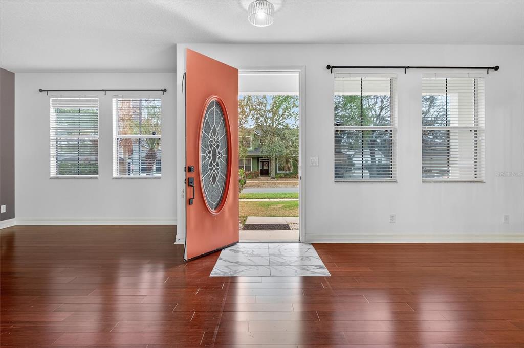 An open front door reveals a view of a neighborhood street from a hardwood-floored room — 3106 ANQUILLA AVENUE, CLERMONT, FL