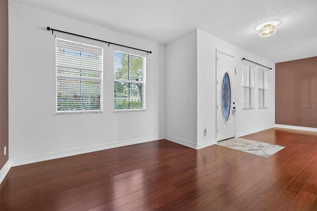An empty room with hardwood floors, white walls, and a front door with a window — 3106 ANQUILLA AVENUE, CLERMONT, FL