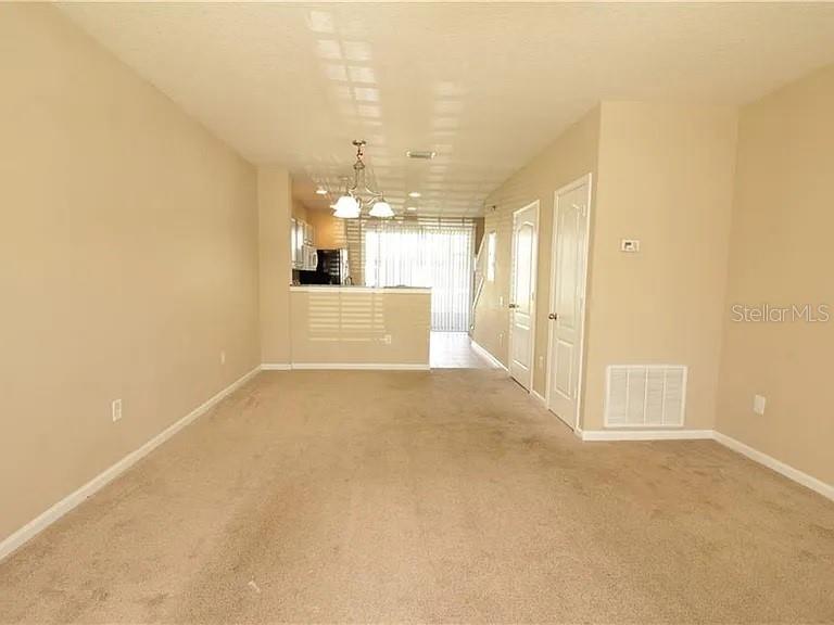 An interior view shows a carpeted living area leading toward a kitchen and sliding glass doors — 4514 BARNSTEAD DRIVE, RIVERVIEW, FL