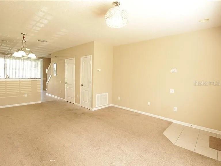 A living room with beige carpet, tan walls, two white doors, and two light fixtures — 4514 BARNSTEAD DRIVE, RIVERVIEW, FL