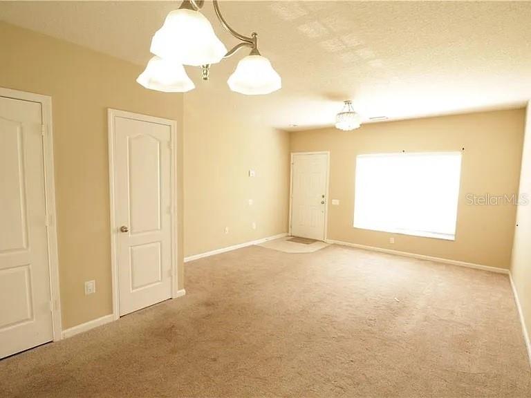 An empty room features beige carpeting, tan walls, two white doors, and two light fixtures — 4514 BARNSTEAD DRIVE, RIVERVIEW, FL