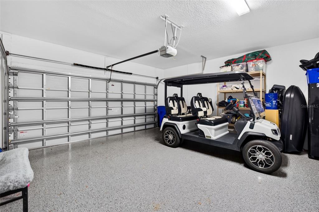 A garage with a gray epoxy floor, a white golf cart, and metal storage shelving — 3266 DUNNING DRIVE, ROYAL PALM BEACH, FL