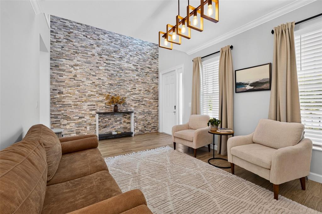 A living room features a stone accent wall, wood-look flooring, and a modern rectangular chandelier — 3266 DUNNING DRIVE, ROYAL PALM BEACH, FL