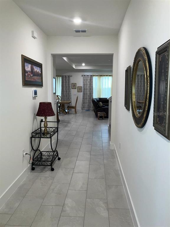 A hallway with gray tile flooring leads into a living area with a dining set — 4258 SW SW 53RD LANE, OCALA, FL