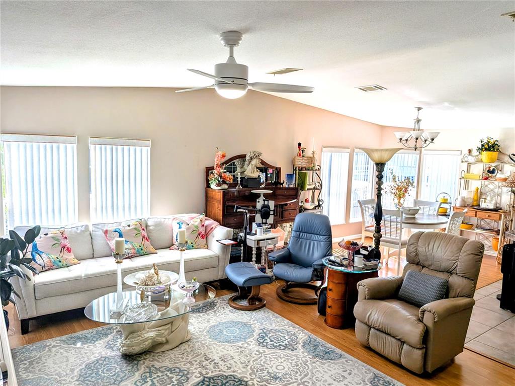 A living room features a white sofa, two armchairs, a glass coffee table, and dining area — 34709 LAKE DRIVE N, PINELLAS PARK, FL