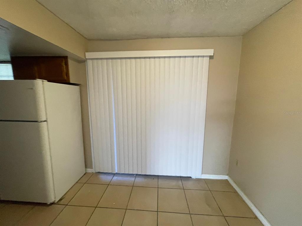 A kitchen area features a white refrigerator, beige walls, and light-colored floor tiles — 1300 ARLINGTON LANE NE UNIT 114, PALM BAY, FL