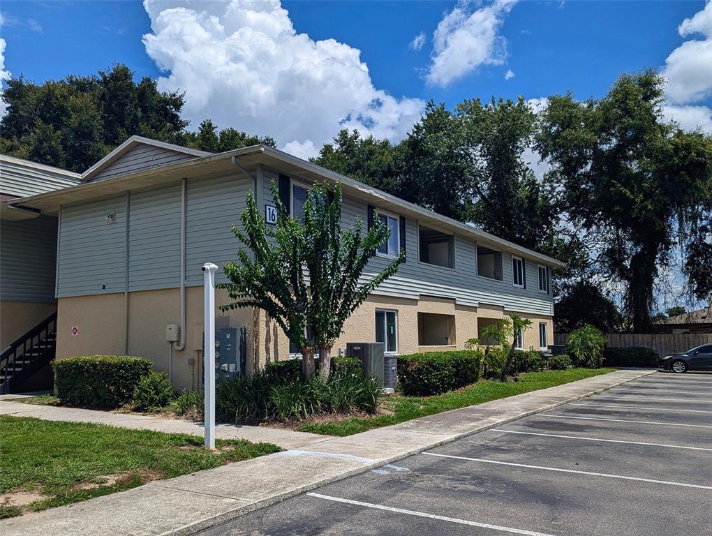 A two-story apartment building with light-colored siding and a parking lot in the foreground — 228 THORN TREE PLACE UNIT 228, BRANDON, FL