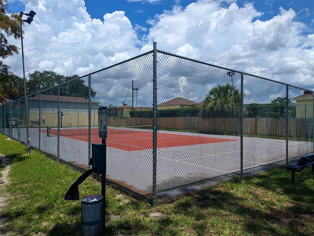 A fenced-in outdoor tennis court with a red and grey surface — 228 THORN TREE PLACE UNIT 228, BRANDON, FL