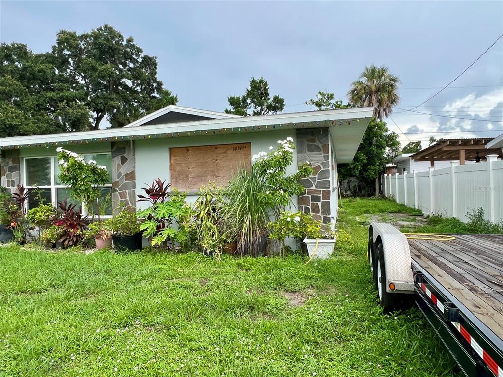 The exterior of a single-story house features a boarded-up window and stone accent siding — 3246 EAGLE STREET, SARASOTA, FL