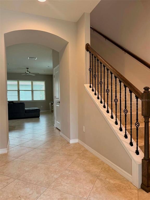 An entryway features tile flooring, an arched doorway, and a staircase with decorative metal railings — 5703 VILLAGE CENTER DRIVE, LITHIA, FL