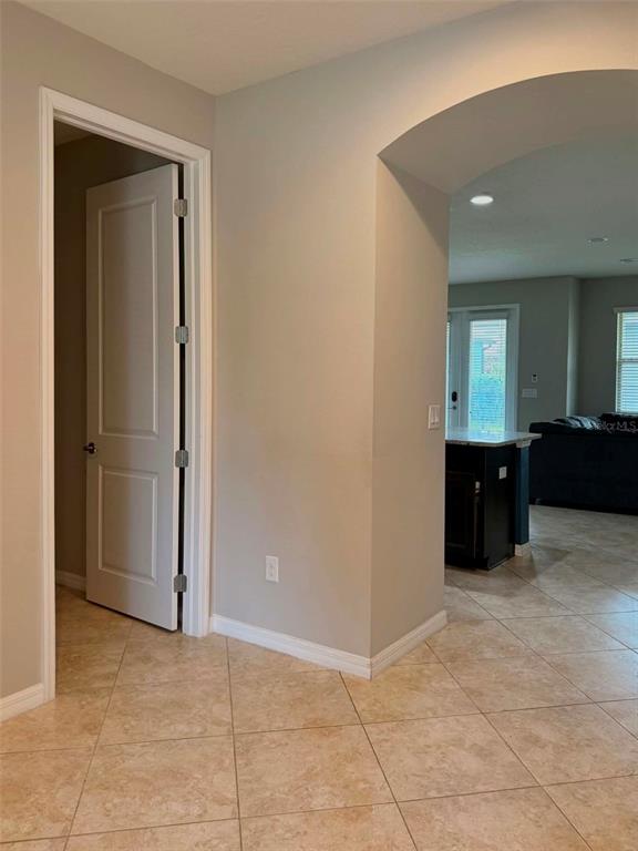A hallway with a white door leads to an open-concept kitchen and living area — 5703 VILLAGE CENTER DRIVE, LITHIA, FL