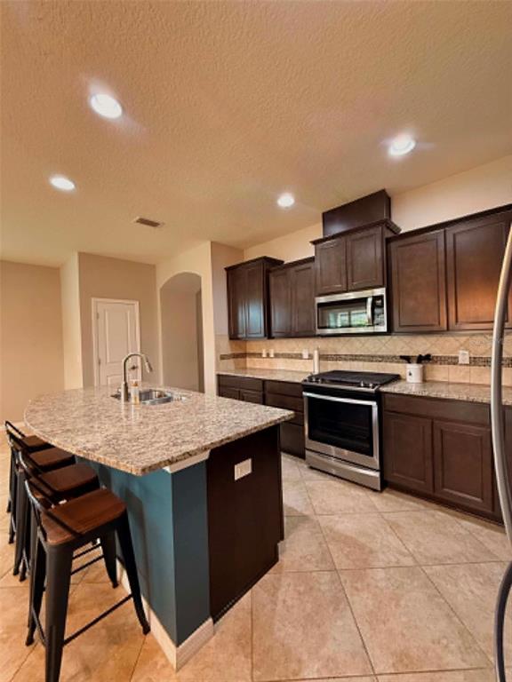 A kitchen featuring dark wood cabinets, granite countertops, a center island, and stainless steel appliances — 5703 VILLAGE CENTER DRIVE, LITHIA, FL