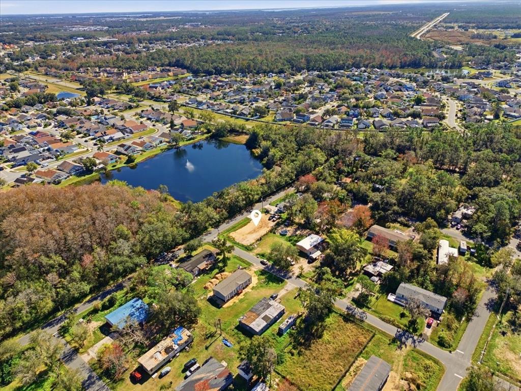 An aerial view shows a vacant lot surrounded by houses, trees, and a nearby pond — 0 HOWISON ROAD, KISSIMMEE, FL