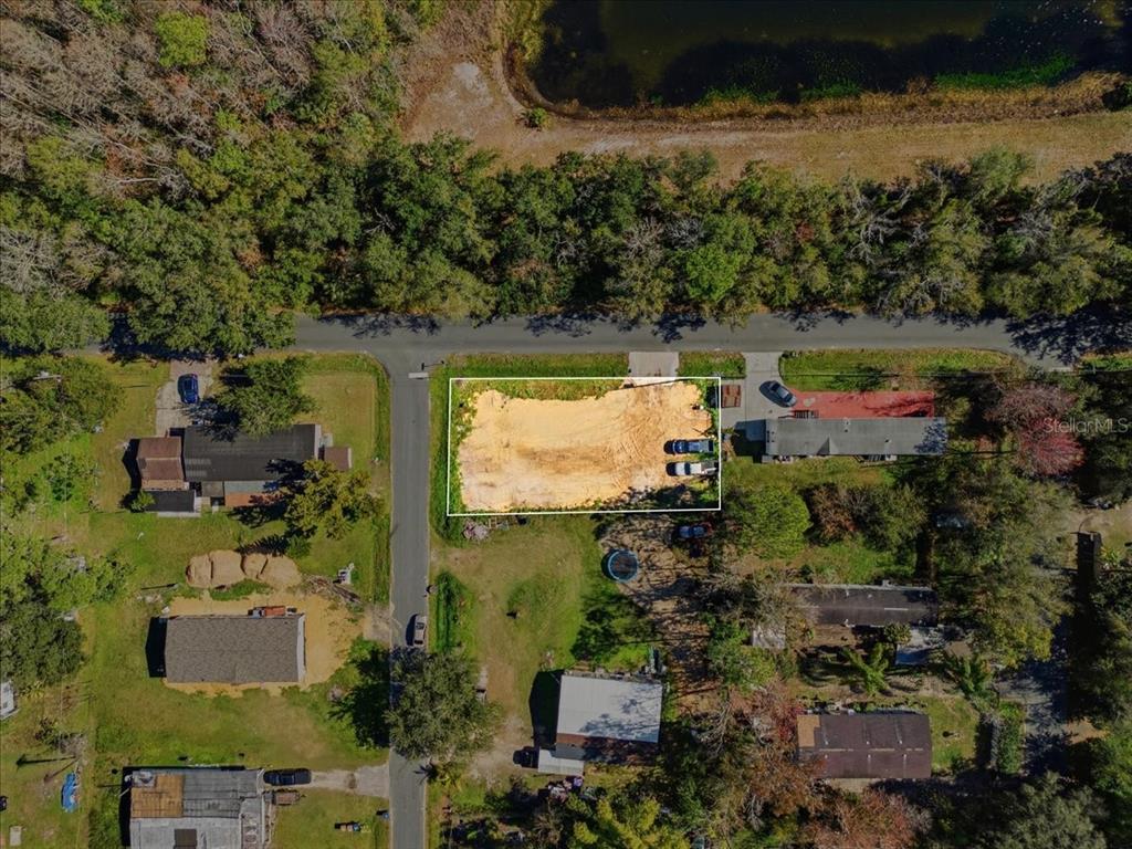 An aerial view shows a rectangular, cleared dirt lot situated between two existing residential properties — 0 HOWISON ROAD, KISSIMMEE, FL