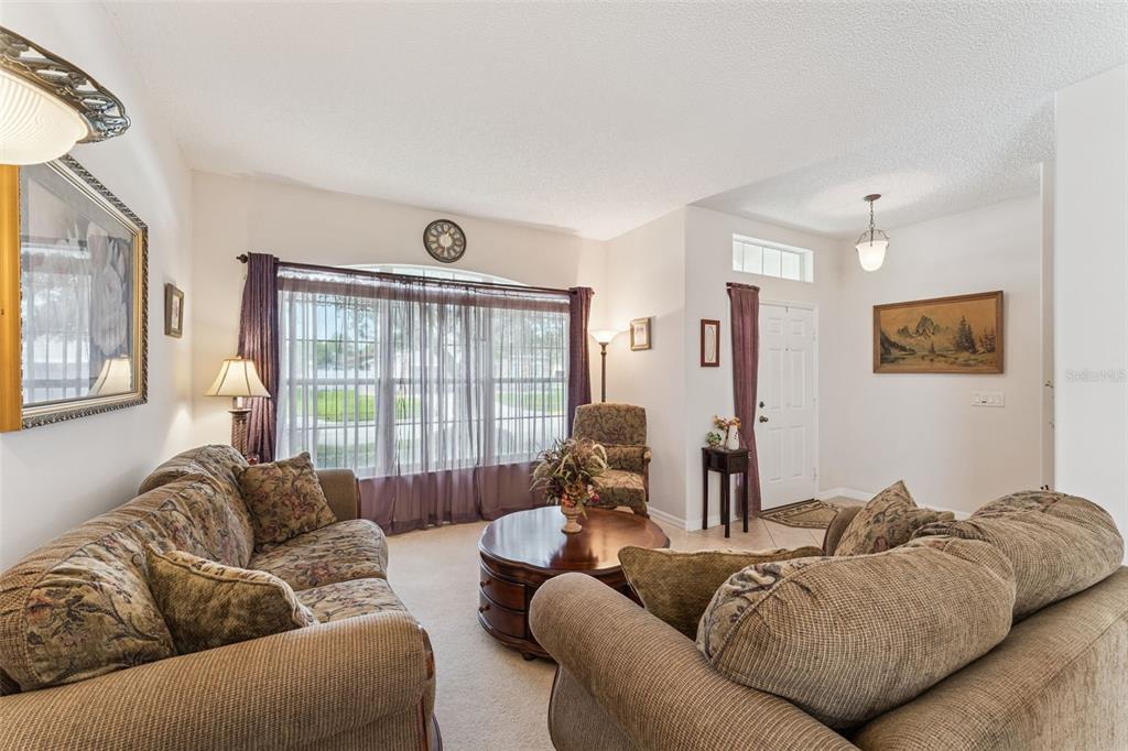 A living room features two patterned sofas, a round coffee table, and a front entryway — 9955 MEDALLION BLUFF LANE, ORLANDO, FL