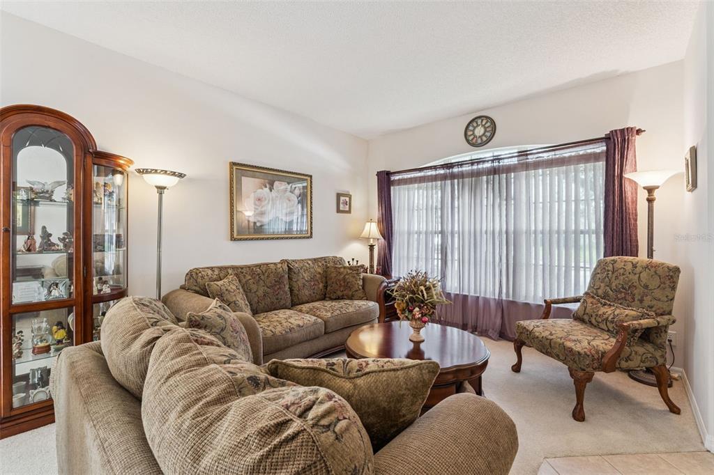 A living room features floral-patterned furniture, a round wooden coffee table, and a large window — 9955 MEDALLION BLUFF LANE, ORLANDO, FL