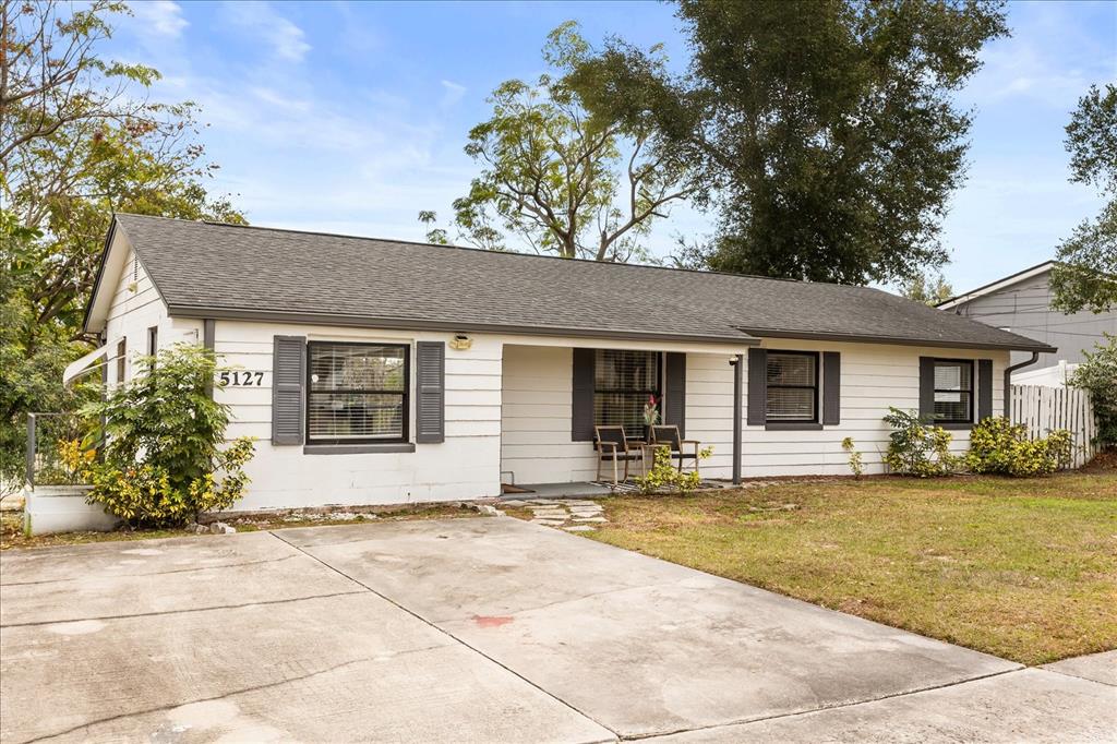 A single-story white house with dark shutters and a concrete driveway sits on a lawn — 5127 GLASGOW AVENUE, ORLANDO, FL