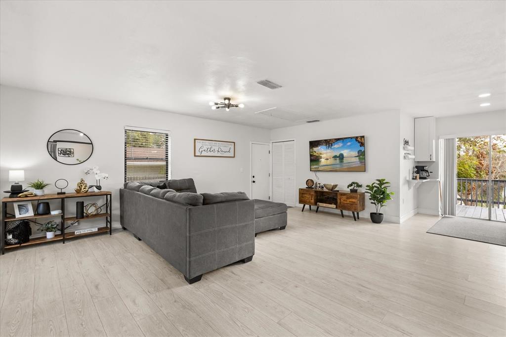 A living room features light wood-look flooring, a gray sectional sofa, and a television console — 5127 GLASGOW AVENUE, ORLANDO, FL