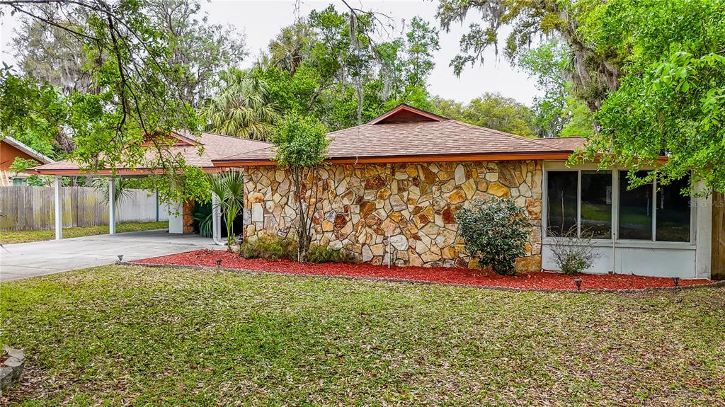 A single-story house with a stone facade, a carport, and a large front lawn — 12 SPRING LAKE WAY, OCALA, FL