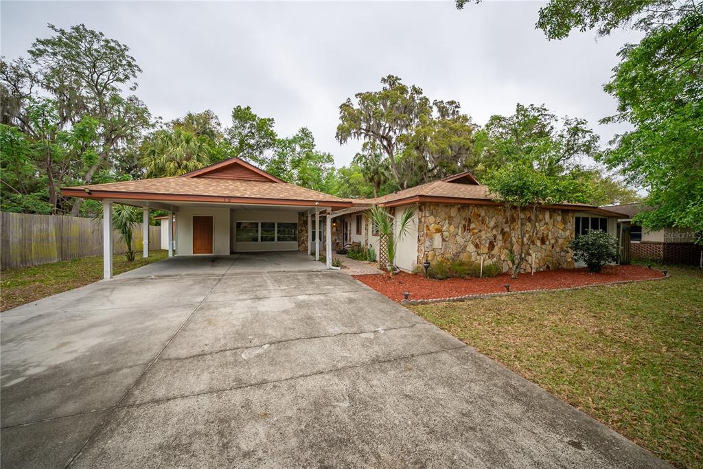 A single-story house with a stone facade, a large carport, and a concrete driveway — 12 SPRING LAKE WAY, OCALA, FL
