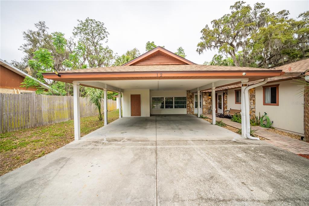 A wide concrete driveway leads to a large covered carport attached to a single-story house — 12 SPRING LAKE WAY, OCALA, FL