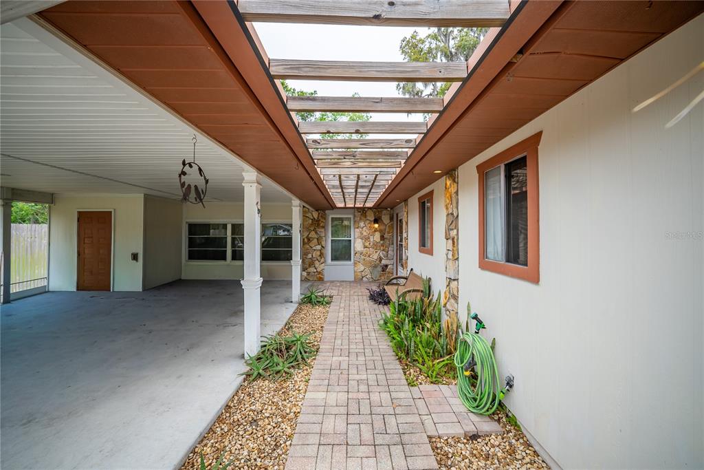 A paved walkway leads toward a stone-accented entrance under a wooden pergola and carport — 12 SPRING LAKE WAY, OCALA, FL