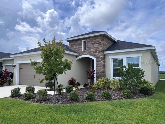 A single-story house features a stone-accented entryway, a two-car garage, and a landscaped front yard — 6085 HIDDEN BRANCH DRIVE, APOLLO BEACH, FL