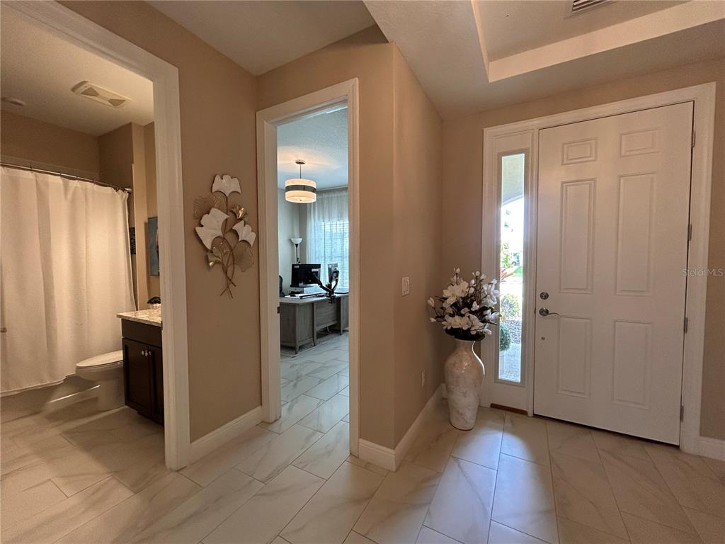 An entryway features light tile flooring, a white front door, and access to a bathroom — 6085 HIDDEN BRANCH DRIVE, APOLLO BEACH, FL