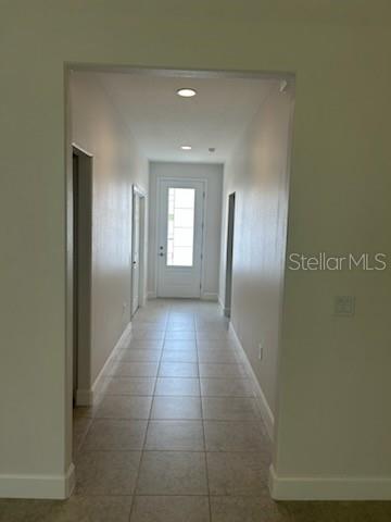 A hallway with light-colored tile flooring leads to a white front door with glass panels — 2623 JUPITER BOULEVARD SW, PALM BAY, FL