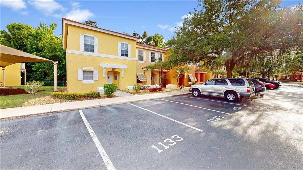 A two-story yellow apartment building features a parking lot with numbered spaces in front — 1135 PARK RIDGE CIRCLE, KISSIMMEE, FL