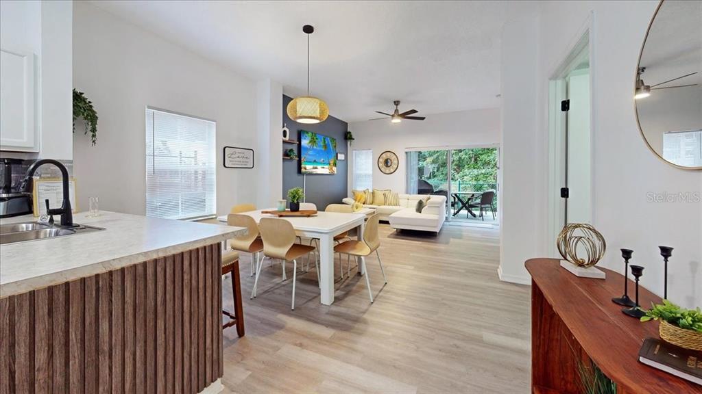An open-concept living and dining area features light wood flooring, a kitchen island, and patio access — 1135 PARK RIDGE CIRCLE, KISSIMMEE, FL