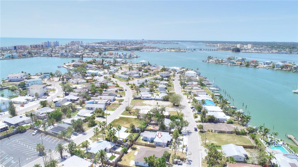 An aerial view shows a coastal neighborhood with houses, streets, and a nearby waterway — 14026 E PARSLEY DRIVE, MADEIRA BEACH, FL