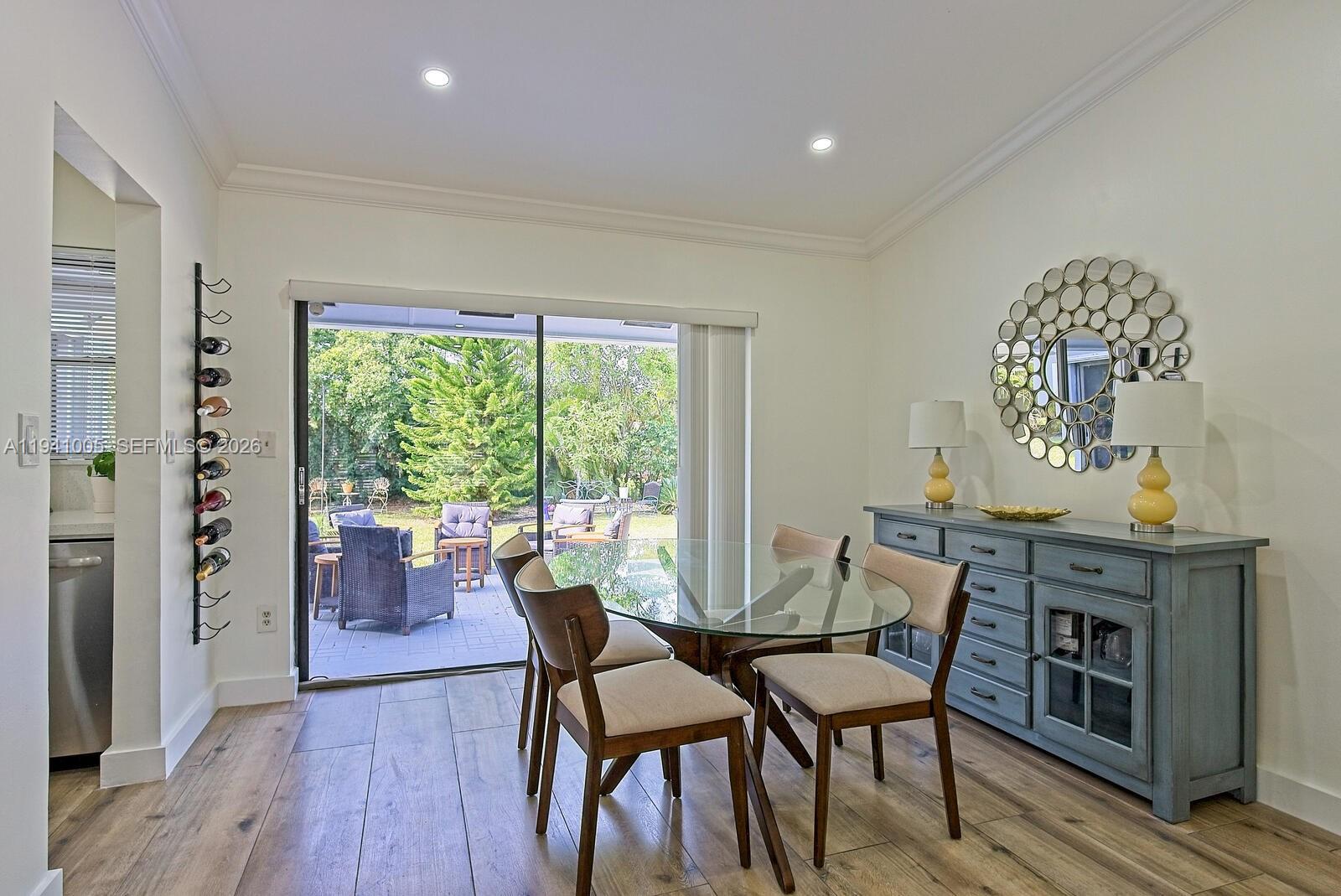 A dining room with a glass table, blue sideboard, and sliding doors opening to a patio — 10900 SW 124th Rd, Miami FL 33176, MIAMI, FL