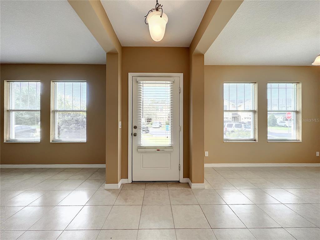 An entryway with light tile flooring, tan walls, and a central white front door — 5597 GELATO DRIVE, ORLANDO, FL