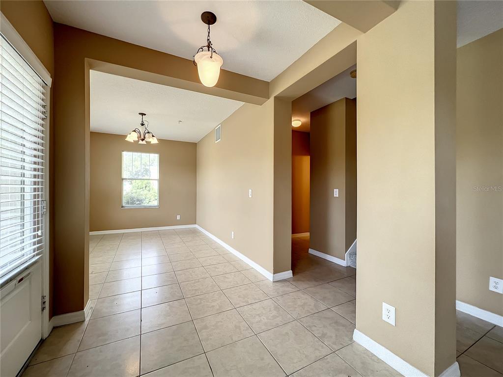A tiled entryway leads to a dining area with two hanging light fixtures and windows — 5597 GELATO DRIVE, ORLANDO, FL