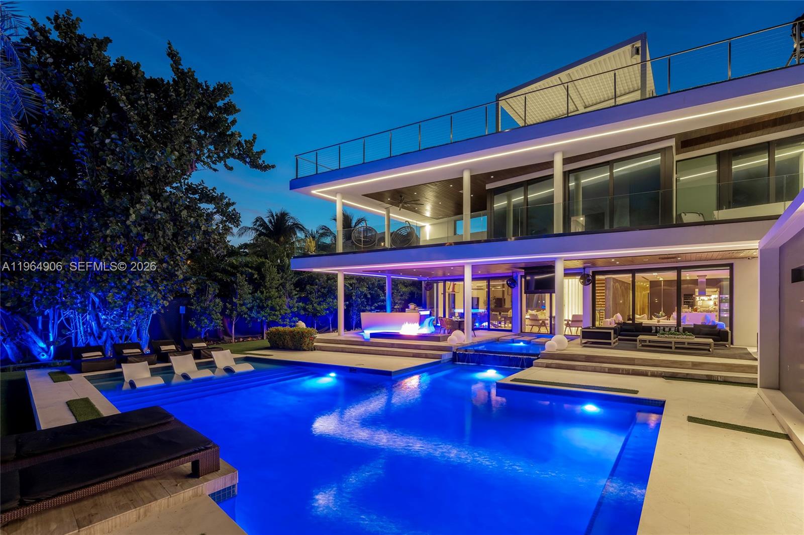 A modern two-story house with a pool, fire feature, and outdoor seating at night — 528 Lakeview Ct, Miami Beach FL 33140, MIAMI BEACH, FL