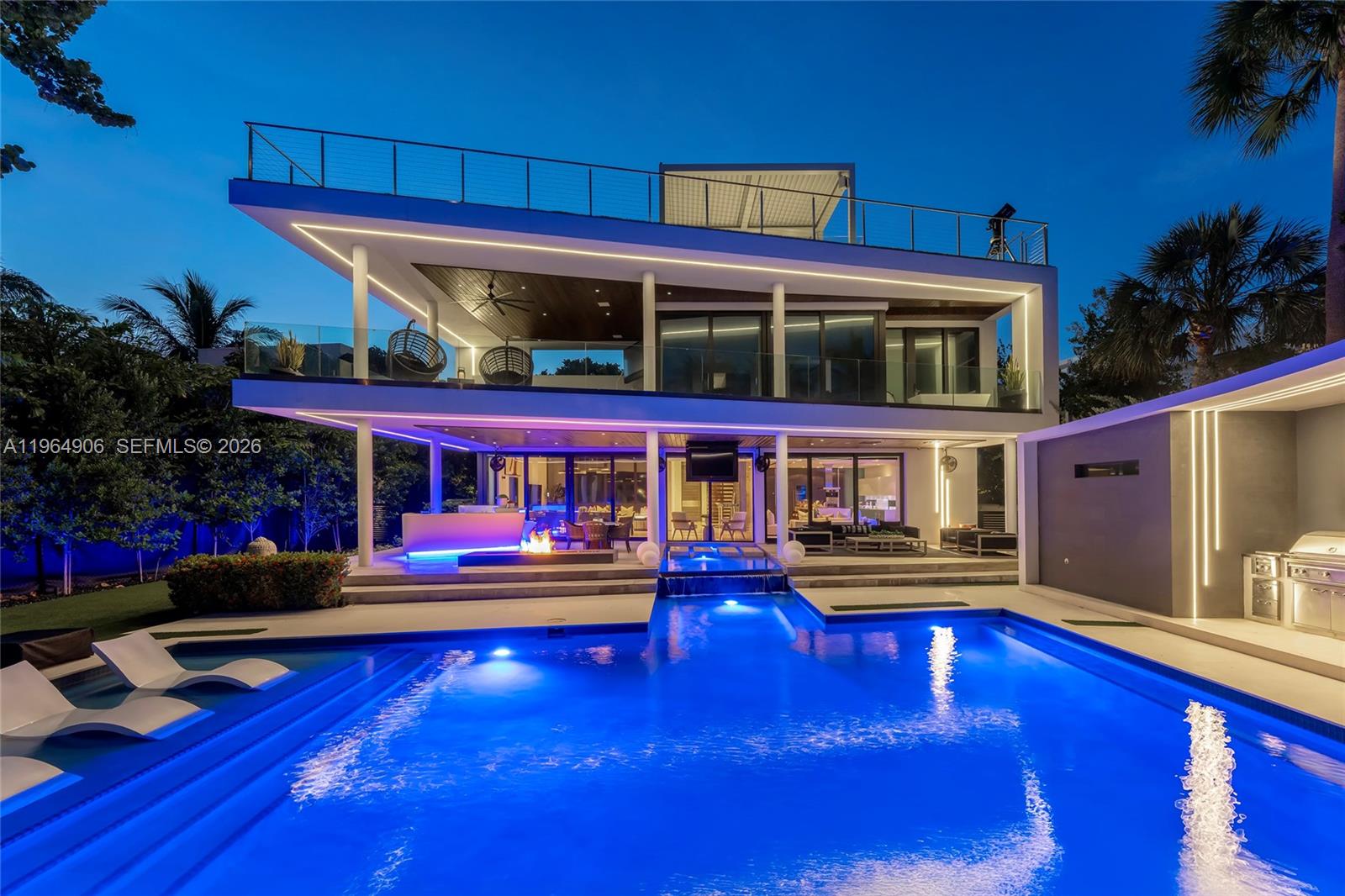 A modern multi-story house with a swimming pool, outdoor fire pit, and illuminated architectural lighting — 528 Lakeview Ct, Miami Beach FL 33140, MIAMI BEACH, FL