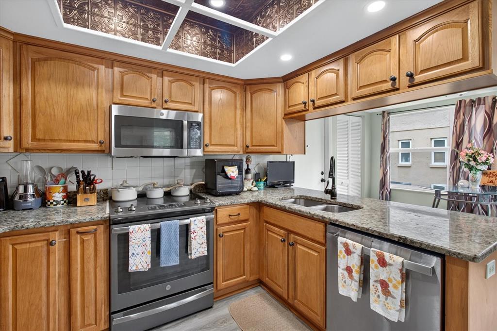 A kitchen with wood cabinets, granite countertops, stainless steel appliances, and a decorative ceiling panel — 10508 QUIMBY DRIVE, PORT RICHEY, FL